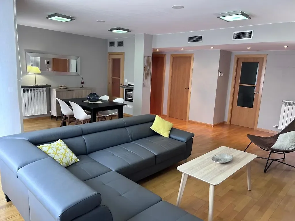 Salón amplio con sofá gris y suelo de parquet